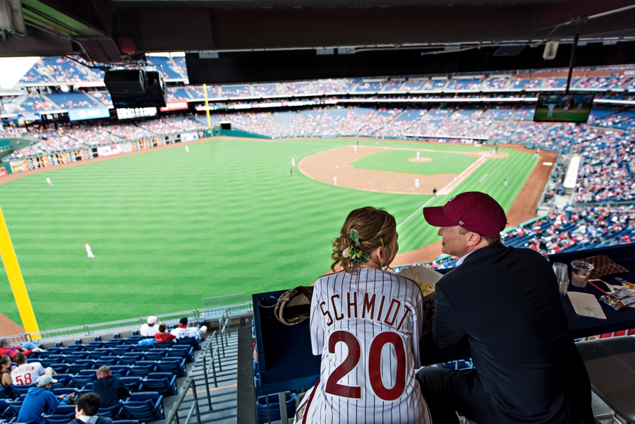 A bride and groom watch the Phillies play at their wedding reception in a Phillies suite.